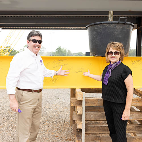 dr. kitts and dena kitts posing in front of signature beam