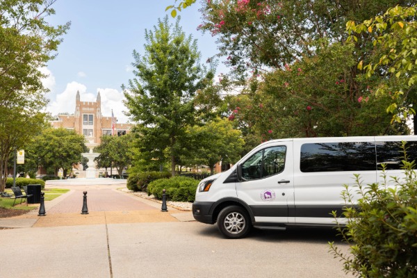 UNA shuttle van in front of Harrison Plaza fountain and 601 Cramer Way Building